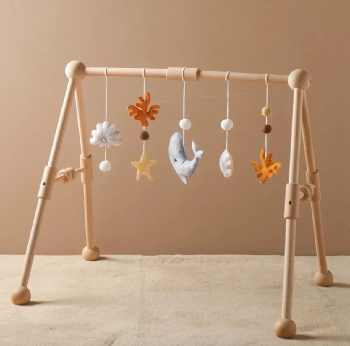 A wooden baby play gym with hanging toys.