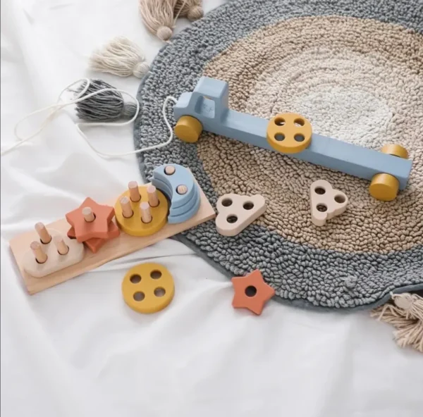 A wooden toy set on the floor next to a rug.