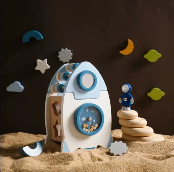 A wooden toy rocket ship in the sand.