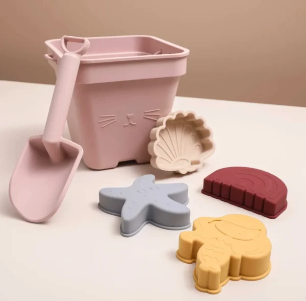 A pink bucket and some sand toys on top of a table.