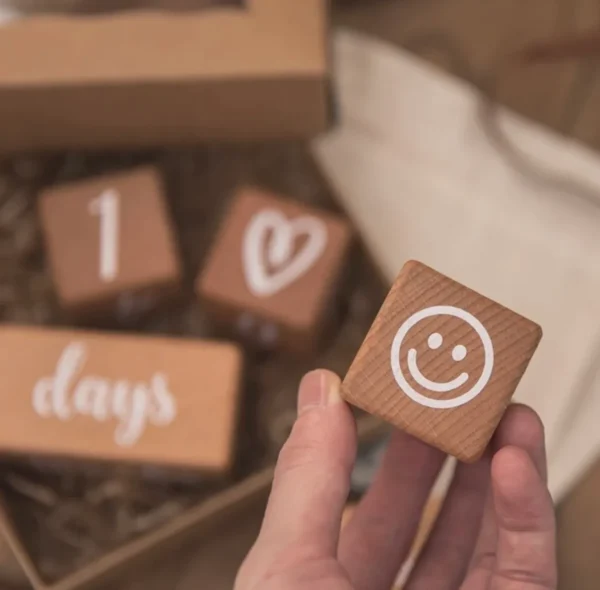 A person holding a wooden block with a smiley face on it.